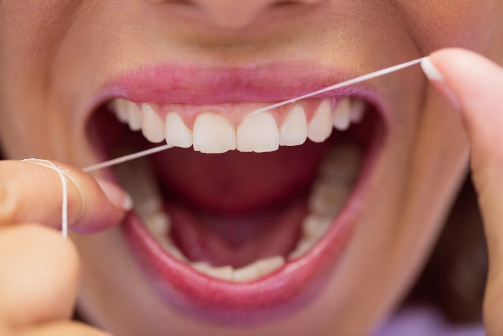 Mulher passando fio dental para prevenir o mau halito