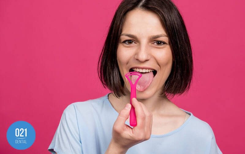 Mulher escovando a língua para evitar a glossite e outras doenças