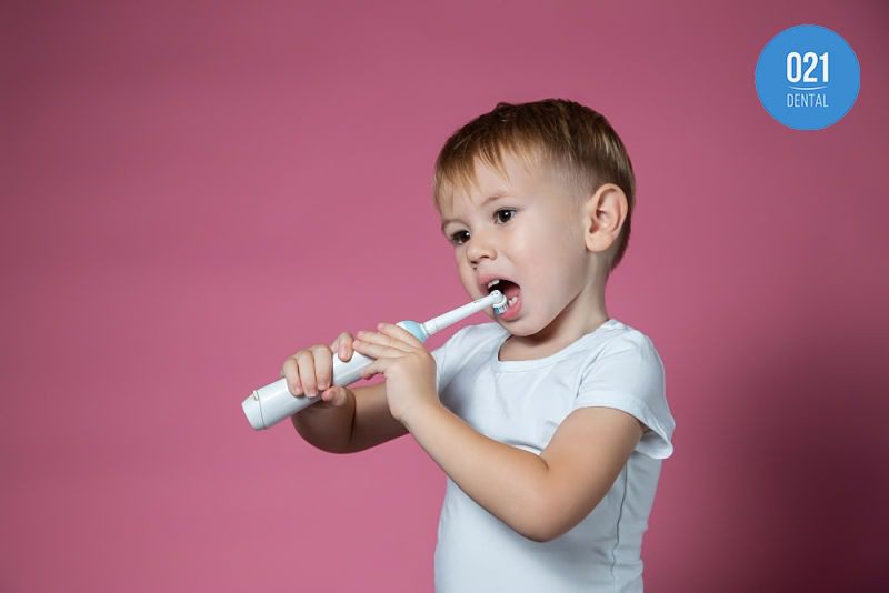 Criança escovando os dentes com escova de dentes elétrica