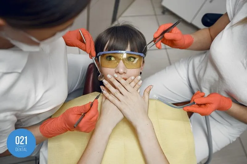 Imagem de uma mulher assustada na cadeira de um dentista