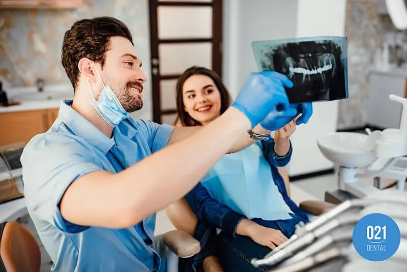 Imagem de um dentista mostrando um raixo x da arcada dentária para paciente