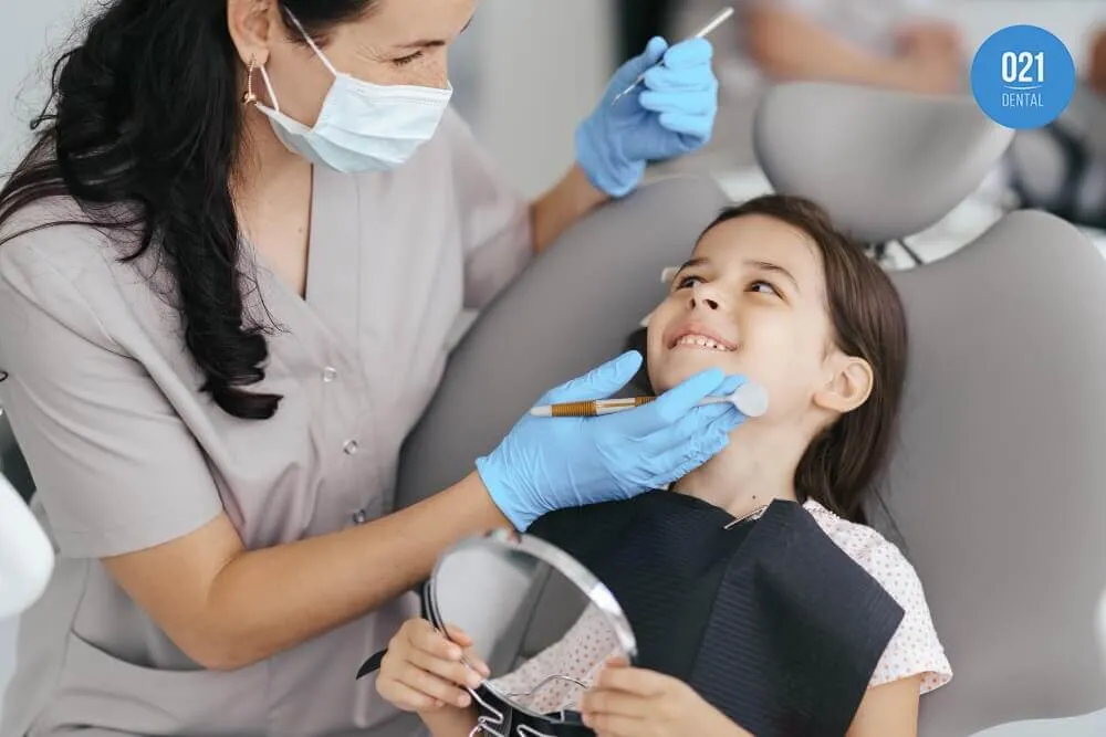 Imagem de uma dentista cuidando da saúde bucal de uma criança em seu consultório odontológico