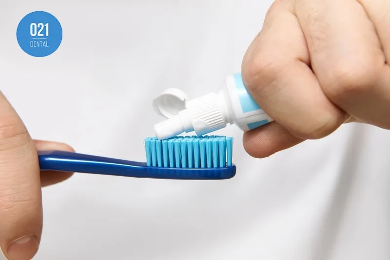 Imagem de uma pessoa colocando pasta na escova de dente
