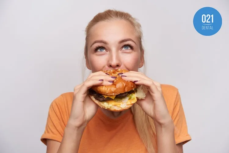 Imagem de uma mulher comendo um hamburguer
