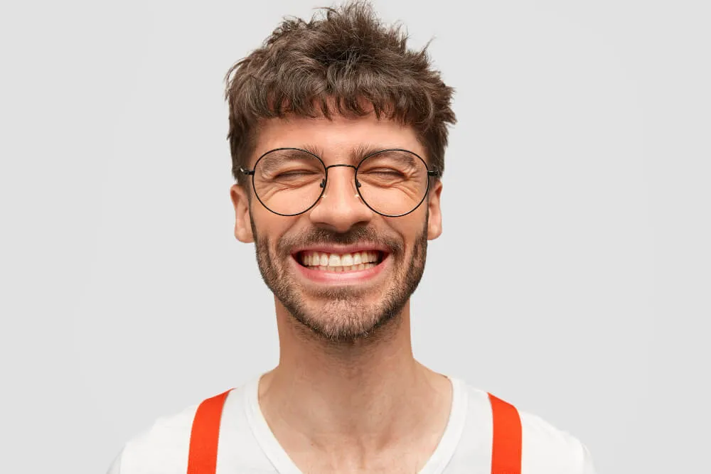 Homem jovem sorrindo com os olhos fechados