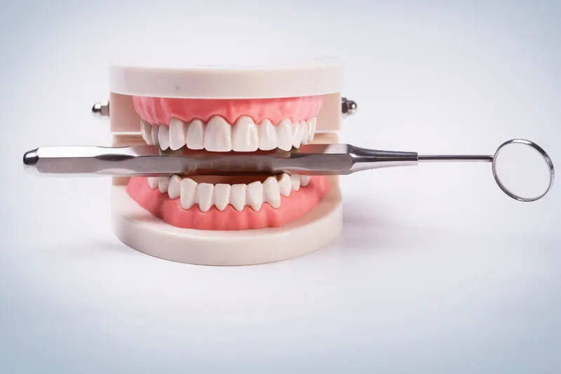 Prótese dental segurando um espelho de dentista