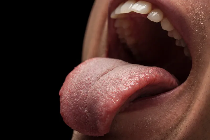Imagem de um rosto com uma pessoa colocando a língua para fora da boca